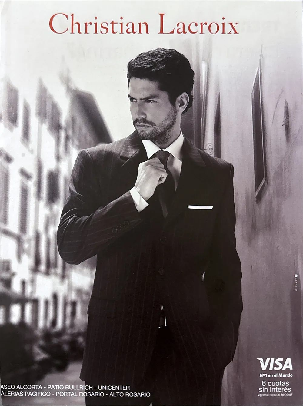 Nacho Valenti Lacroix in a chalk-stripe suit, adjusting his tie, Christian Lacroix campaign